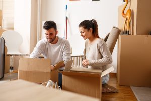 Young couple unpacking cardboard boxes at new home.Moving house.