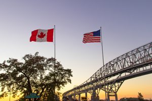 American and Canadian flags waving at sunset